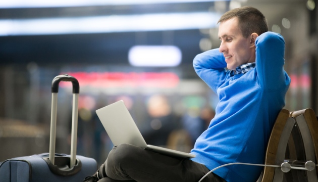 Man ontspant met laptop en koffer op luchthaven.