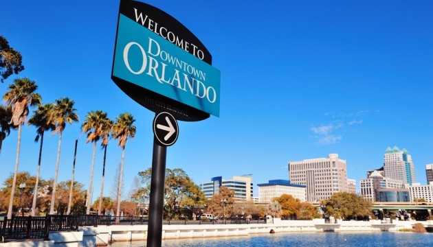 Welkomstbord bij Downtown Orlando met stad op achtergrond.