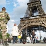 Militairen en toeristen bij de Eiffeltoren, Parijs.