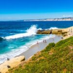 Zonnig strand met golven en mensen in zee.