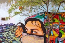 Kleurrijke muurschildering van vrouw met bomen op achtergrond.