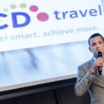 Man houdt toespraak voor BCD Travel-presentatie.