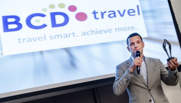 Man houdt toespraak voor BCD Travel-presentatie.