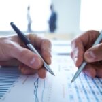 Twee zakenlieden bespreken financiële grafieken op papier.