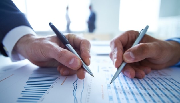 Twee zakenlieden bespreken financiële grafieken op papier.