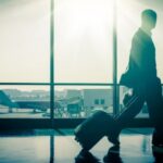 Silhouet reiziger op luchthaven met koffer, vliegtuig buiten.