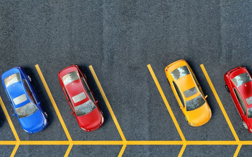Luchtfoto van geparkeerde gekleurde auto's op asfalt.