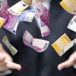 Vliegende eurobiljetten tussen open handen.