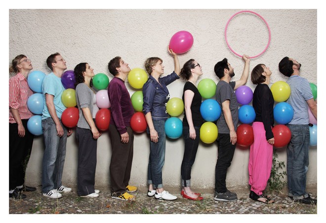 Mensen rij met kleurrijke ballonnen aan muur.