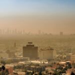 Stad onder smog met skyline op achtergrond.