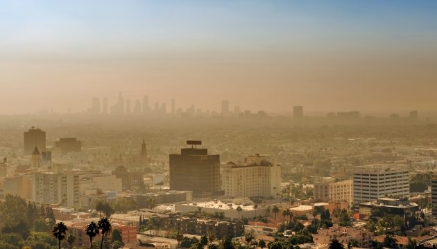 Stad onder smog met skyline op achtergrond.