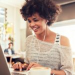 Blije vrouw werkt op laptop in café.