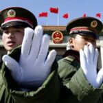 Twee soldaten in uniform voor Chinees gebouw met vlaggen.