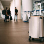 Koffer in luchthaven met reizigers op achtergrond