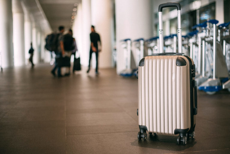 Koffer in luchthaven met reizigers op achtergrond