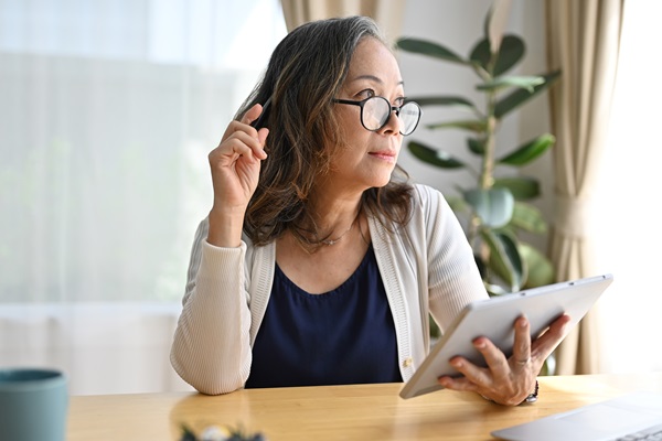 Mulher com um tablet, a pensar numa secretária.