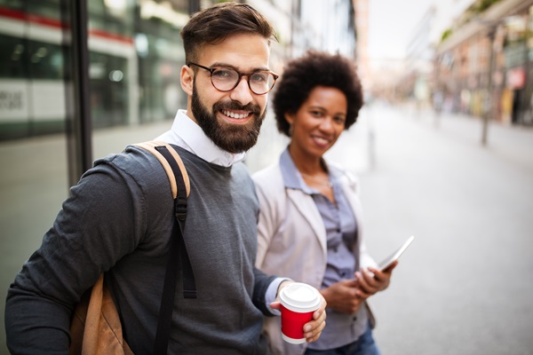 Duas pessoas a sorrir ao ar livre com um café e um tablet.
