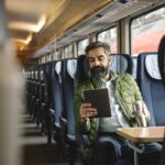 homem sentado no comboio a utilizar um tablet