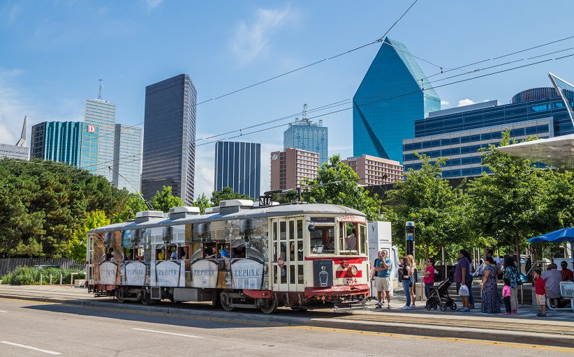 Os passageiros de uma avenida ensolarada na área de Dallas esperam para embarcar num carro elétrico.