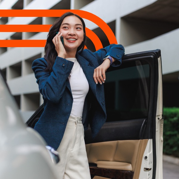 Smiling woman on phone beside open car door