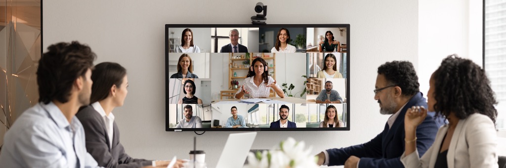 Team meeting with video conference displayed on wall monitor