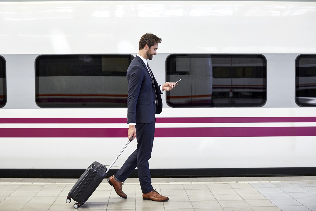 Business traveler checks phone beside high-speed train