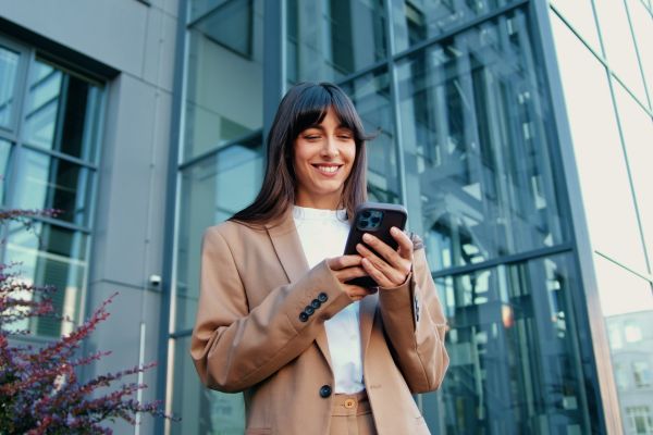 Woman using smartphone outside modern glass office building