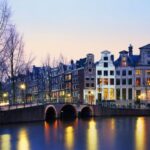 Amsterdam canal and historic buildings at dusk.