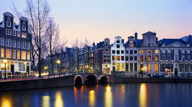 Amsterdam canal and historic buildings at dusk.