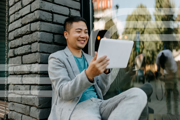 Man sitting outdoors using a digital tablet