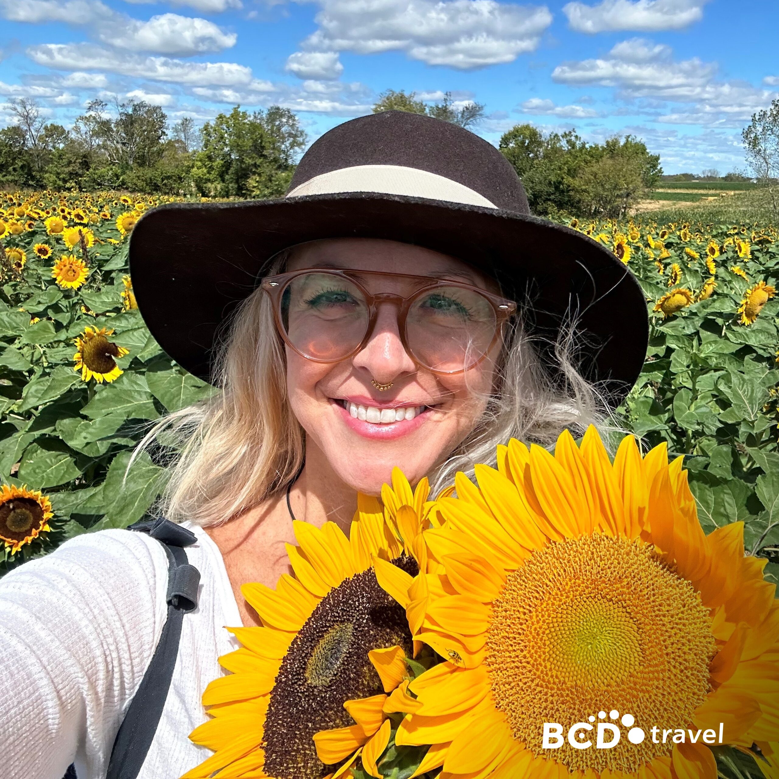 Smiling woman in sunflower field, sunny day.