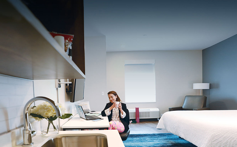 Woman working in modern hotel room with laptop.