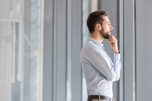 Thoughtful businessman gazing through modern office windows
