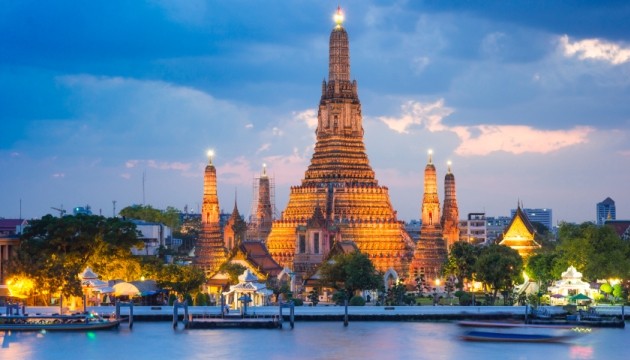 Wat Arun temple at sunset, Bangkok skyline view.