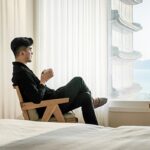 Person sipping coffee, enjoying ocean view from window.