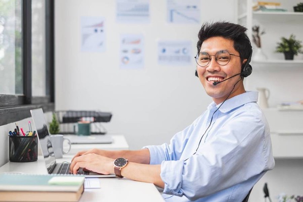 Smiling customer service agent wearing headset at laptop