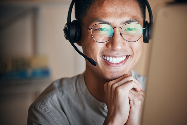 Smiling person with headset working on computer.