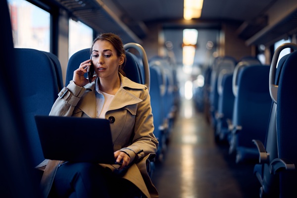 Woman using laptop and phone on train