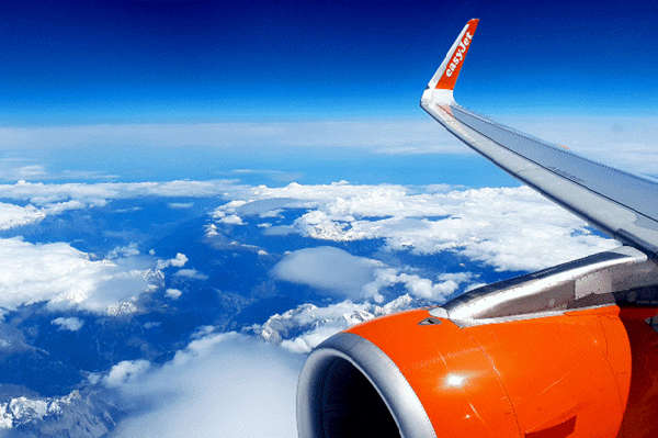 Airplane wing and engine above clouds