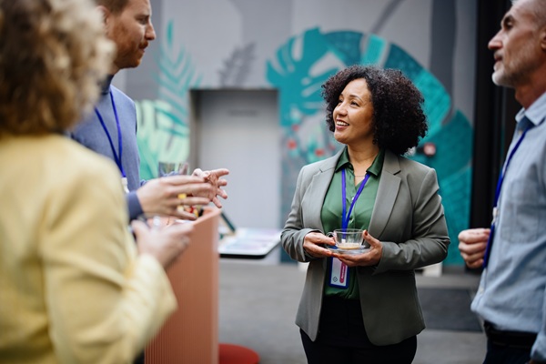 Professionals networking at conference with coffee and badges