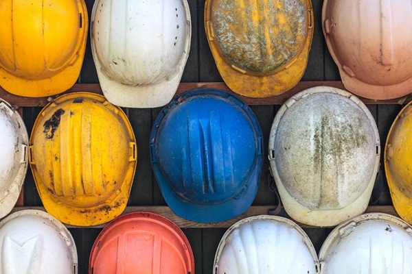 Colorful worn construction hard hats arranged in rows