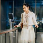Woman with luggage using access control gate.