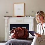 Woman in suit using tablet near leather bag.