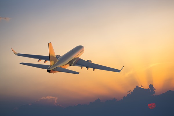 Airplane flying into sunset sky