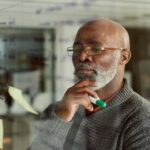 A professional person looks thoughtful while reviewing notes in a conference room.