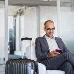 Man in business suit using phone at airport.