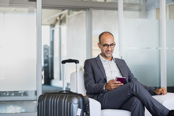 Man in business suit using phone at airport.