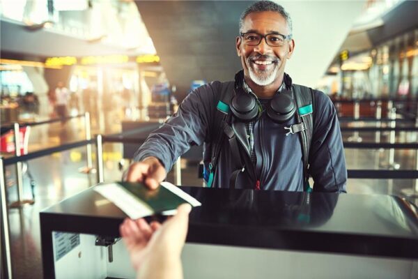 Smiling traveler handing passport at airport checkpoint.