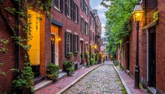 Cobblestone street with red brick buildings and lampposts.