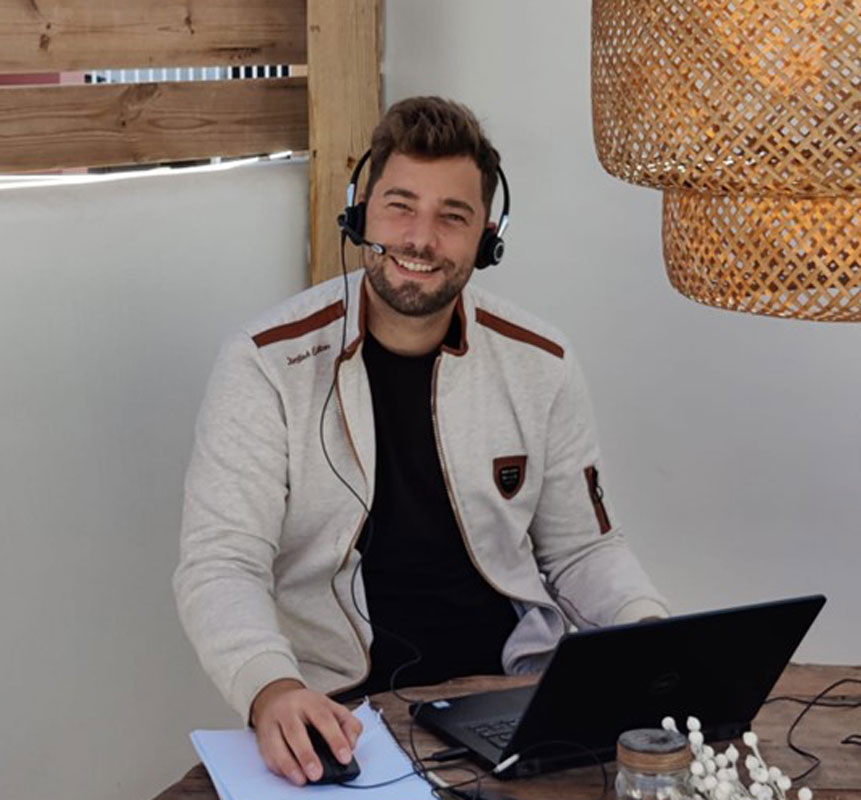 Smiling man wearing headset works on laptop